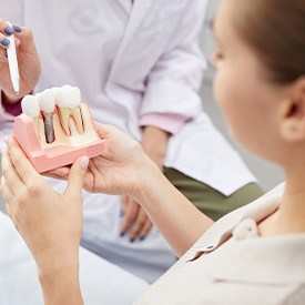 A patient holding a large dental implant model while talking to a dentist