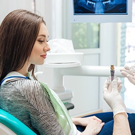 A dentist showing a dental implant to a woman