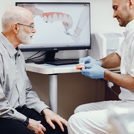 Dentist showing patient implant denture