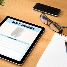 Dental insurance form on tablet next to notepad